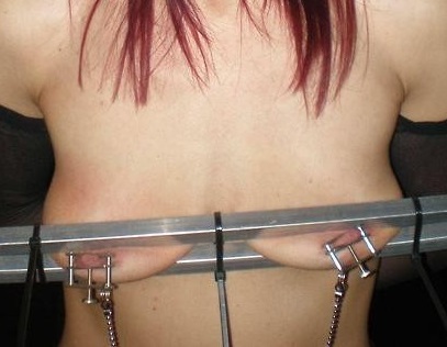 乳首クリップで乳首を挟まれて乳房全体を圧迫されている女性
